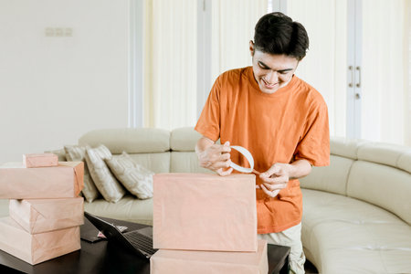Happy Young Entrepreneur Packing Orders for Online Business from Homeの写真素材