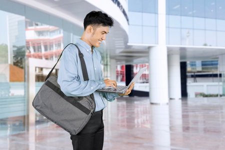 Young Professional Man Working on Laptop in Modern Office Buildingの写真素材