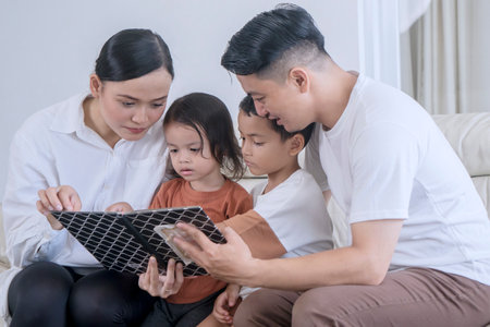 Loving Parents Reading a Storybook to Their Children at Homeの写真素材