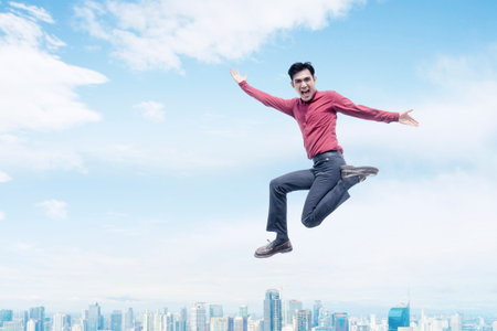 Energetic Young Man Leaping Above City Skylineの写真素材