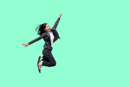 Happy Businesswoman Jumping with Joy on a Mint Green Backgroundの写真素材