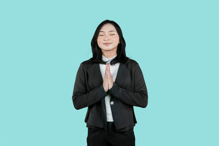 Businesswoman Practicing Gratitude with Hands in Prayer Pose on Turquoise Background
