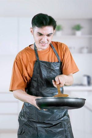 Focused Home Chef Stirring Food in Modern Kitchenの写真素材