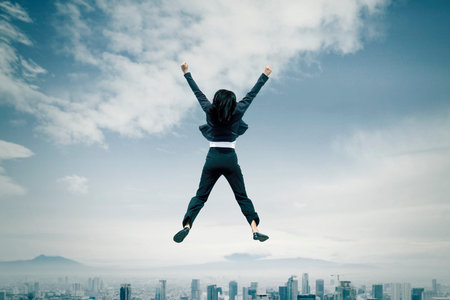 Confident Businesswoman Celebrating Success Above a City Skylineの写真素材