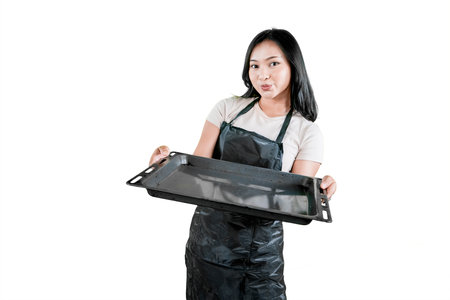 Smiling Female Chef Holding a Baking Tray in a Playful Poseの写真素材