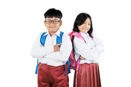 Confident Asian Schoolboy and Schoolgirl Standing Back to Back with Backpacksの写真素材