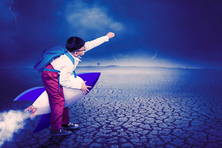 Creative Concept of Young Student Riding Rocket Through Dramatic Landscapeの写真素材