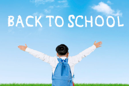 Happy Indonesian Student Raising Hands with â€œBack to Schoolâ€ Sky Text on Blue Background
