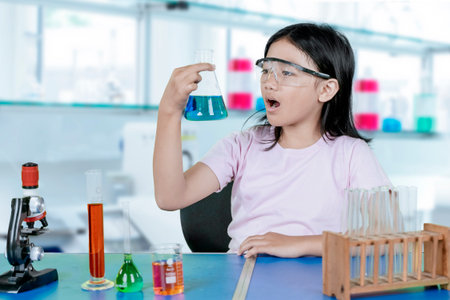 Amazed young girl observing chemical reaction in science lab during school experimentの写真素材