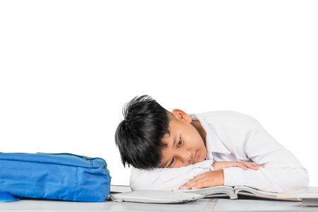 Tired Student Lying on Desk with Head on Book Looking Exhaustedの写真素材