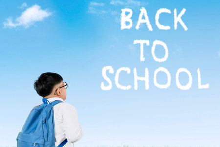 Indonesian Schoolboy with Backpack Looking at âBack to Schoolâ Text in Sky on a Clear Dayの写真素材