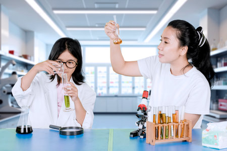 Mother and Daughter Conducting Chemistry Experiment in Modern Science Laboratoryの写真素材