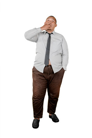 Tired overweight businessman yawning and covering mouth while standing isolated on white backgroundの写真素材