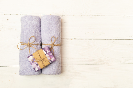 Soft clean towels and a piece of natural soap are laid on a light wooden background. Copy space. Flat layout. View from above.の写真素材