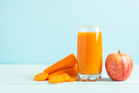 Fresh carrot and apple juice in a glass on a wooden blue background. Selective focus. Copy space.の写真素材