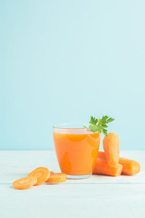 A glass of fresh carrot juice on a wooden blue background. Selective focus. Copy space.の写真素材