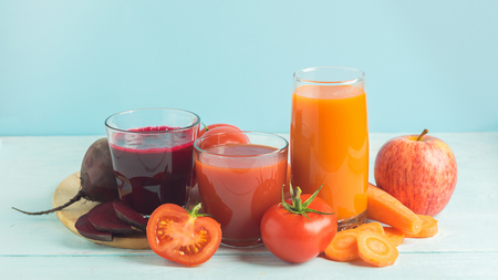Fresh juice smoothies from a variety of vegetables beetroot apple carrot tomatoes in glasses on wooden blue background.の写真素材