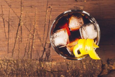 Strong alcoholic drink of brandy whiskey in a glass with ice cubes on a dark wooden background. Top view . Copy space.の写真素材