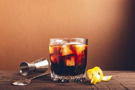 A glass of strong alcoholic drink whiskey brandy a glass glass with ice cubes dark wooden...