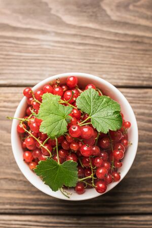 Fresh ripe red currant berry in a white cup on a dark wooden background. View from above.の写真素材