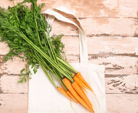 Fresh natural organic carrot bag made of cotton wooden rustic background. Natural organic products. Ecology concept.の写真素材