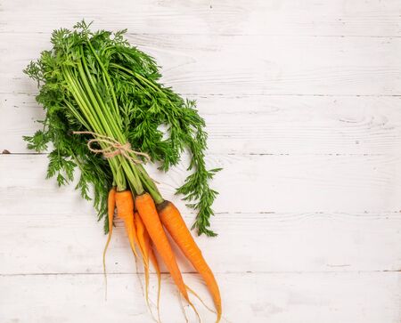 Fresh natural organic carrots bunch rustic wooden background. Autumn summer harvest concept. Top view flat layout.の写真素材