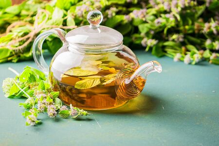 Fresh aromatic tea with melissa mint leaves glass teapot on a rustic background. Healing herbal drink. Horizontal frame.の写真素材