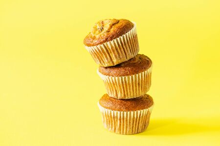 Stack of banana muffins on a yellow background. Healthy vegan dessert. Horizontal frame. Copy space.の写真素材