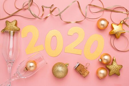 The symbol of the new year, numbers 2020 cut out of gold paper on pink paper background. New Year or...