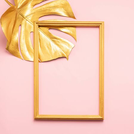 Monstera tropical plant leaf and frame painted gold pink background. Art concept minimalism. Vertical frame.の写真素材