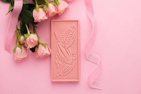 Chocolate pink handmade tile and rose flowers on a pink background. Minimalism holiday concept. Top...