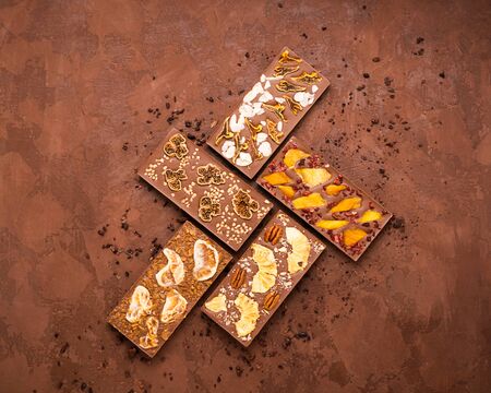 Chocolate whole tiles of various types of milky white dark on a brown background. Flat layout top...