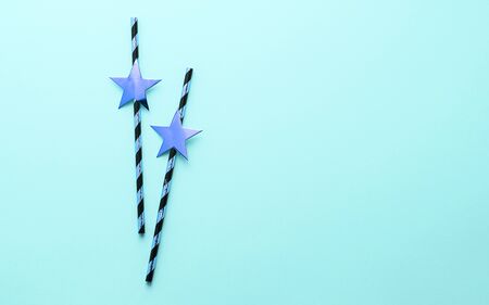 Shiny paper straws with golden stars on a pastel blue background. Copy space meso text design. Flat layoutの写真素材