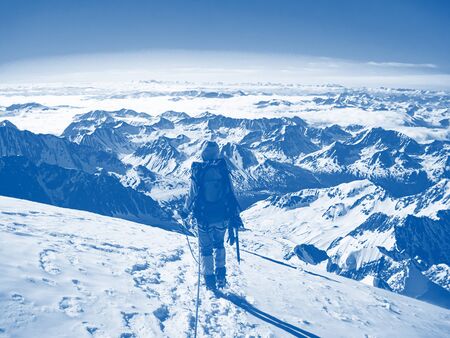 Man climber on top of a beautiful snow-capped mountain. The concept of extreme recreation and...