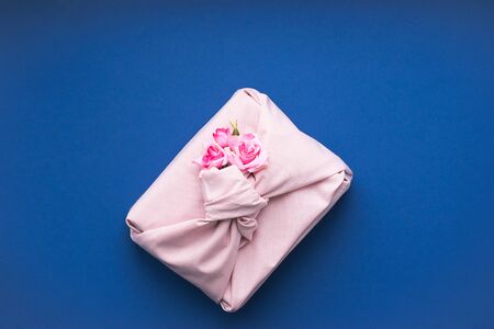Holiday gift wrapped fabric in the manner of Furoshiki on a fashionable blue background. Concept...