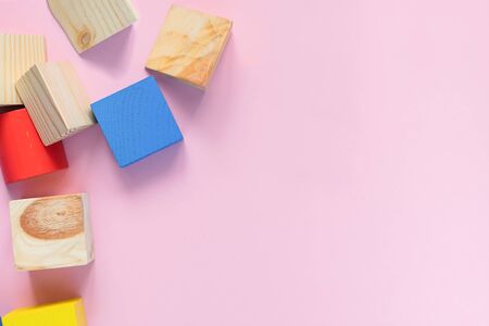 Childrens wooden toys on a pink background concept zero west. Frame from developing colored cubes....