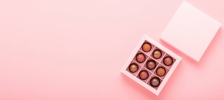 Chocolate truffle candies in a box pink background. Gifts festive food love concept. Horizontal...