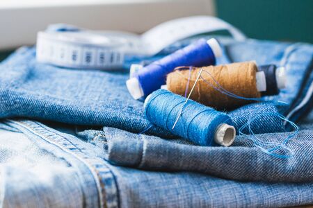 Handicraft, repair and tailoring. Sewing accessories threads close-up denim wooden table. Horizontal frameの写真素材