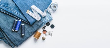 Handicraft, clothing repair. Ripped blue jeans sewing accessories white background. The concept of...