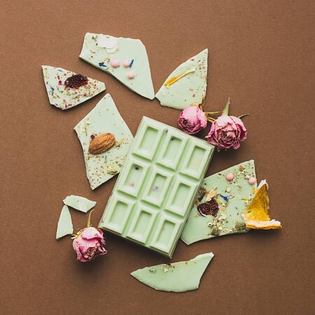 Chocolate bar whole with the addition of pistachios brown background. Top view flat layout. Square...