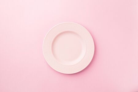 Empty plate pastel pink background. Flat lay copy space. Minimalistic monochrome concept.の写真素材