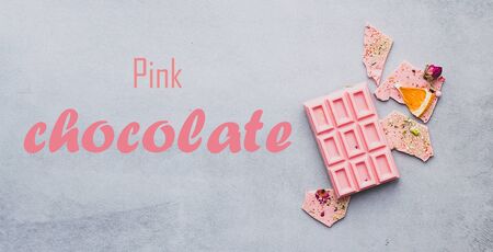 Chocolate pink whole bar decorated with slices of fruits nuts and slices on a gray text Chocolate...