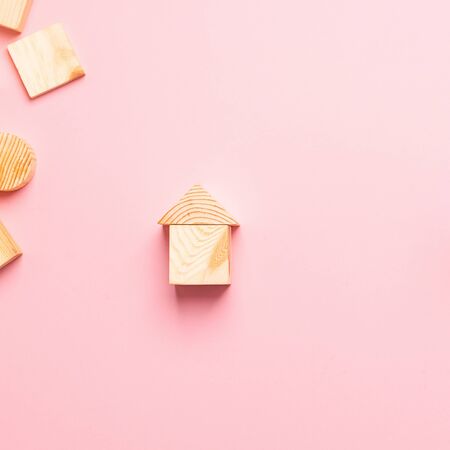 House made of wooden cubes on a pink background. The concept of building houses from environmentally friendly materials.の写真素材
