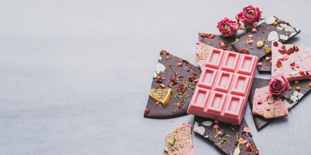 Chocolate pink whole bar decorated with slices of fruits nuts and slices on a gray background. Minimization monochrome. Top view flat mockup. Horizontal frame. Mockup templateの写真素材