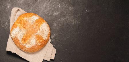 One bun of freshly baked bread on a black