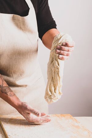 Concept process of making alternative yeast-free home-made bread. A man kneads a kneading pot with dough on the table.の写真素材