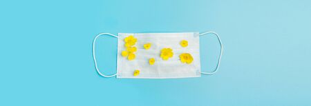 Protective medical mask and fresh flowers on a blue background. Flat layout place for text your design concept healthの写真素材