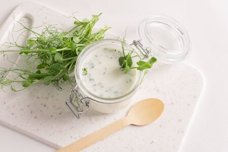 Sour milk product drink with the addition of fresh micro grass sprouts greens on a white kitchen table.の写真素材