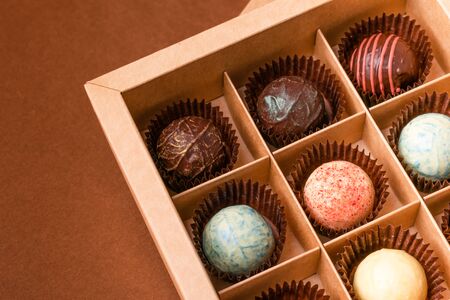 Chocolate candies truffle from various chocolate toppings in a box with a satin ribbon against a...