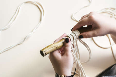 Female hands weave macrame the home workshop. Boho lifestyle. Hobby hobby concept. Selective focus...